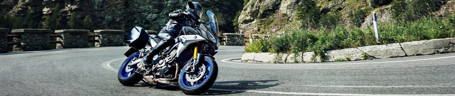Rider in full gear taking a sharp turn around a corner on a motorcycle